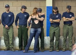 A woman hugs a firefighter before the start of a memorial service, Monday, July 1, 2013 in Prescott, Ariz. The service was held for the 19 Granite Mountain Hotshot Crew firefighters who were killed Sunday, when an out-of-control blaze overtook the elite group. (AP Photo/Julie Jacobson)